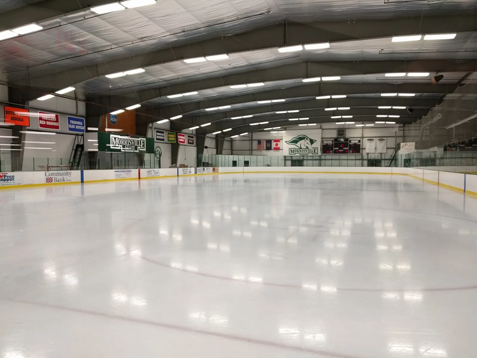 The empty ice sheet at SUNY Morrisville IcePlex with the college logo and the boards — SUNY Morrisville IcePlex