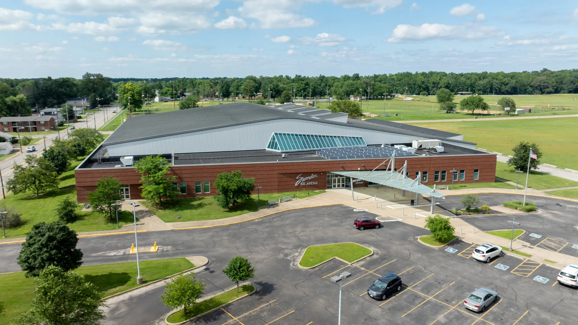 Aerial over the brick frontage and glass entrance canopy — Swonder Ice Arena