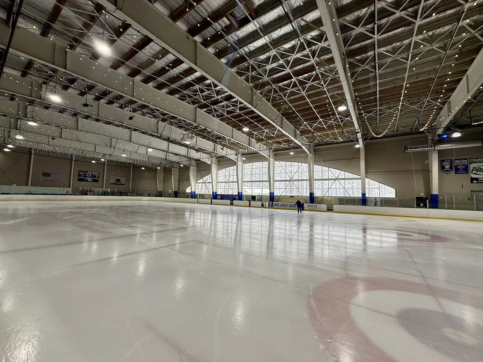 The empty ice at South Lake Tahoe Ice Arena under its steel-trussed arched roof, with the curved clerestory windows at the far end — Tahoe Ice Arena