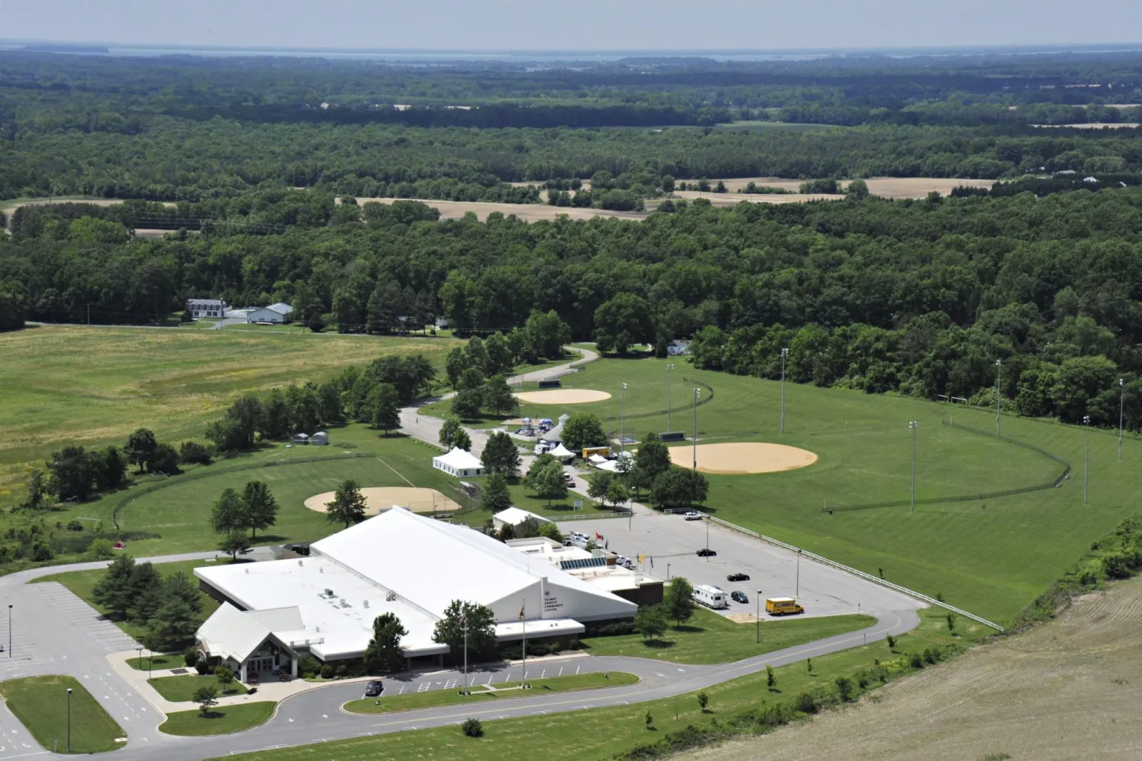 Vista aérea del Talbot County Community Center, un edificio de techo blanco con letreros de 'TALBOT COUNTY COMMUNITY CENTER' sobre la entrada, rodeado de estacionamientos y campos de beisbol — Talbot County Community Center