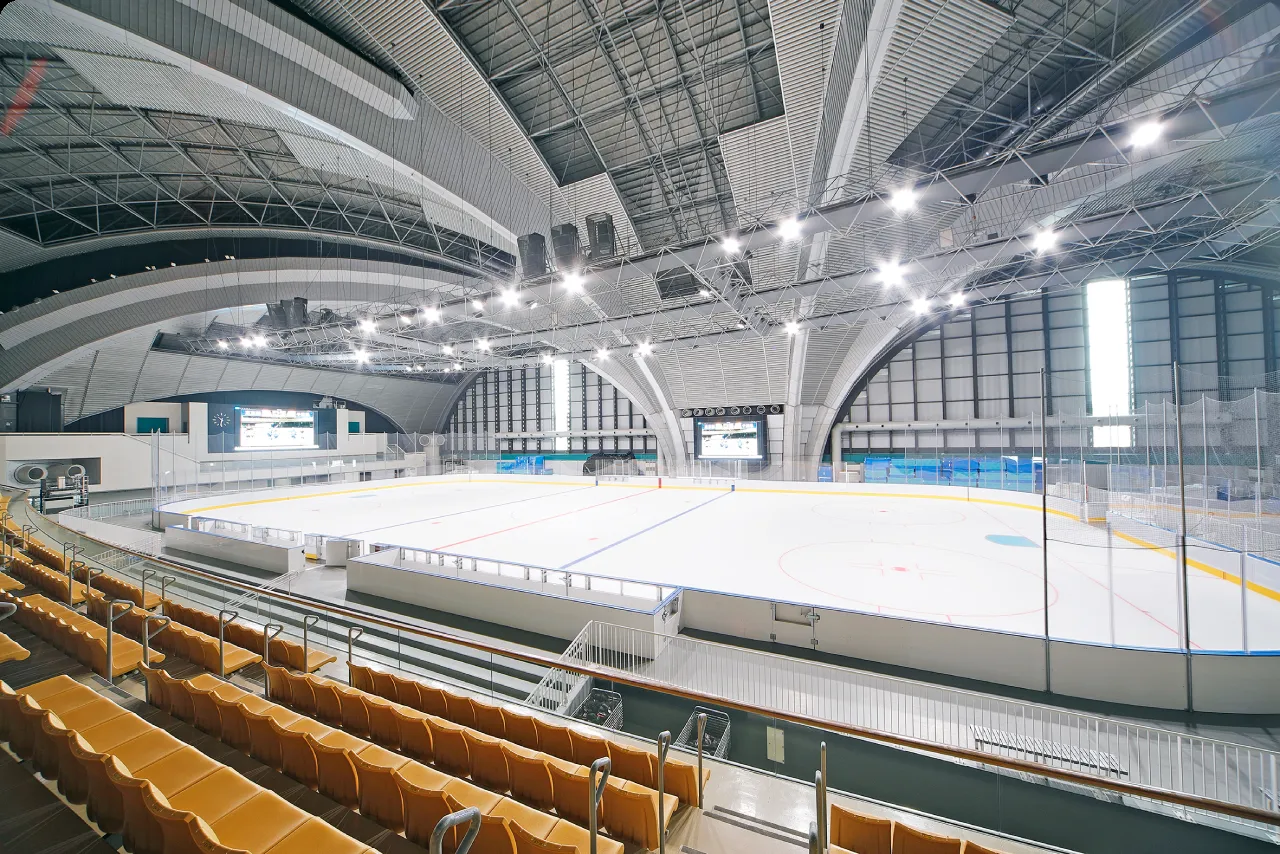 客席とアーチ形の屋根のある、無人のメインリンク — Tanaka Kikinzoku Ice Arena (Tokyo Tatsumi Ice Arena)