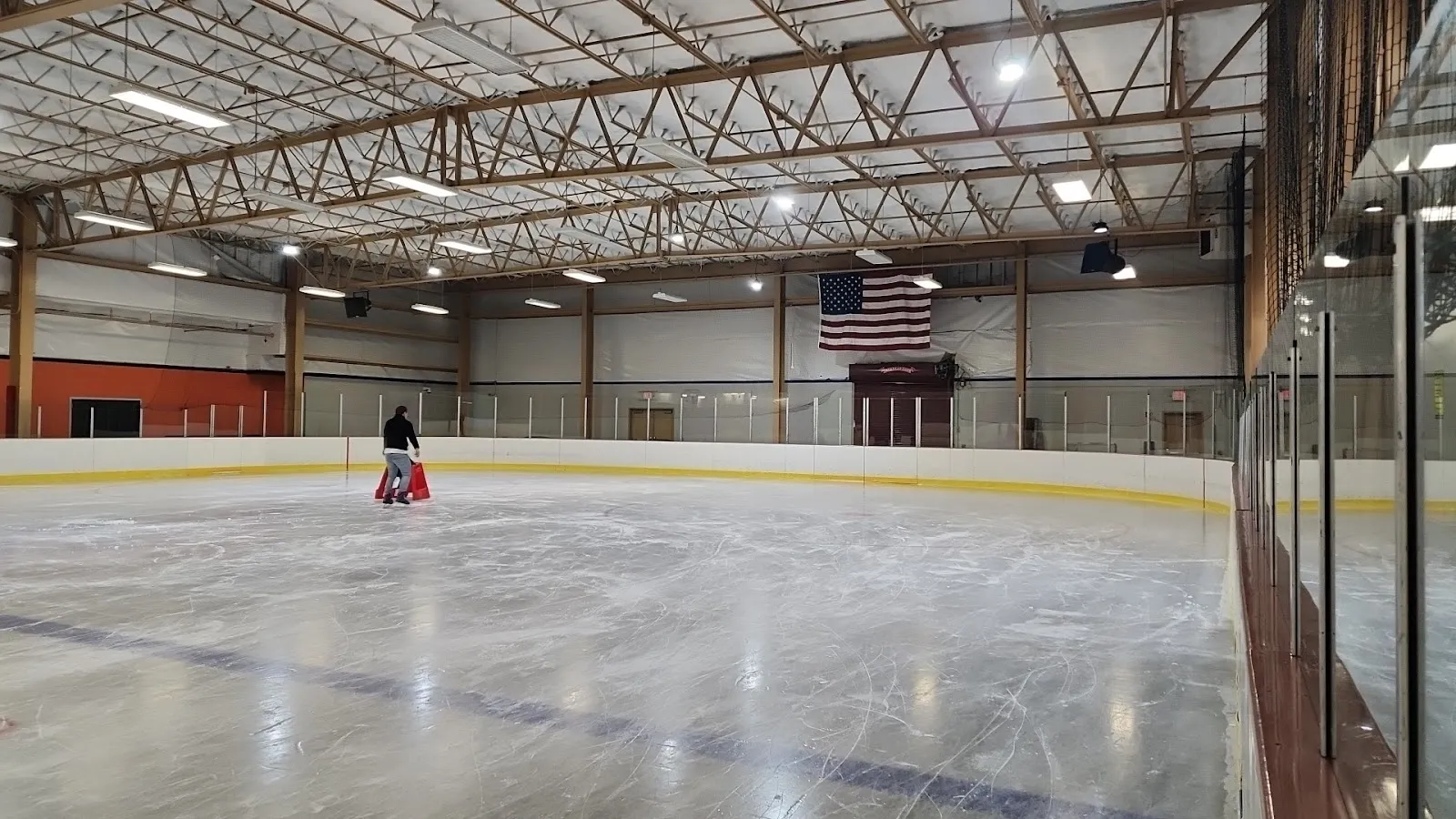 The indoor ice at Tarken with its boards, steel roof trusses and a lone skater at the far end. — Tarken Ice Rink