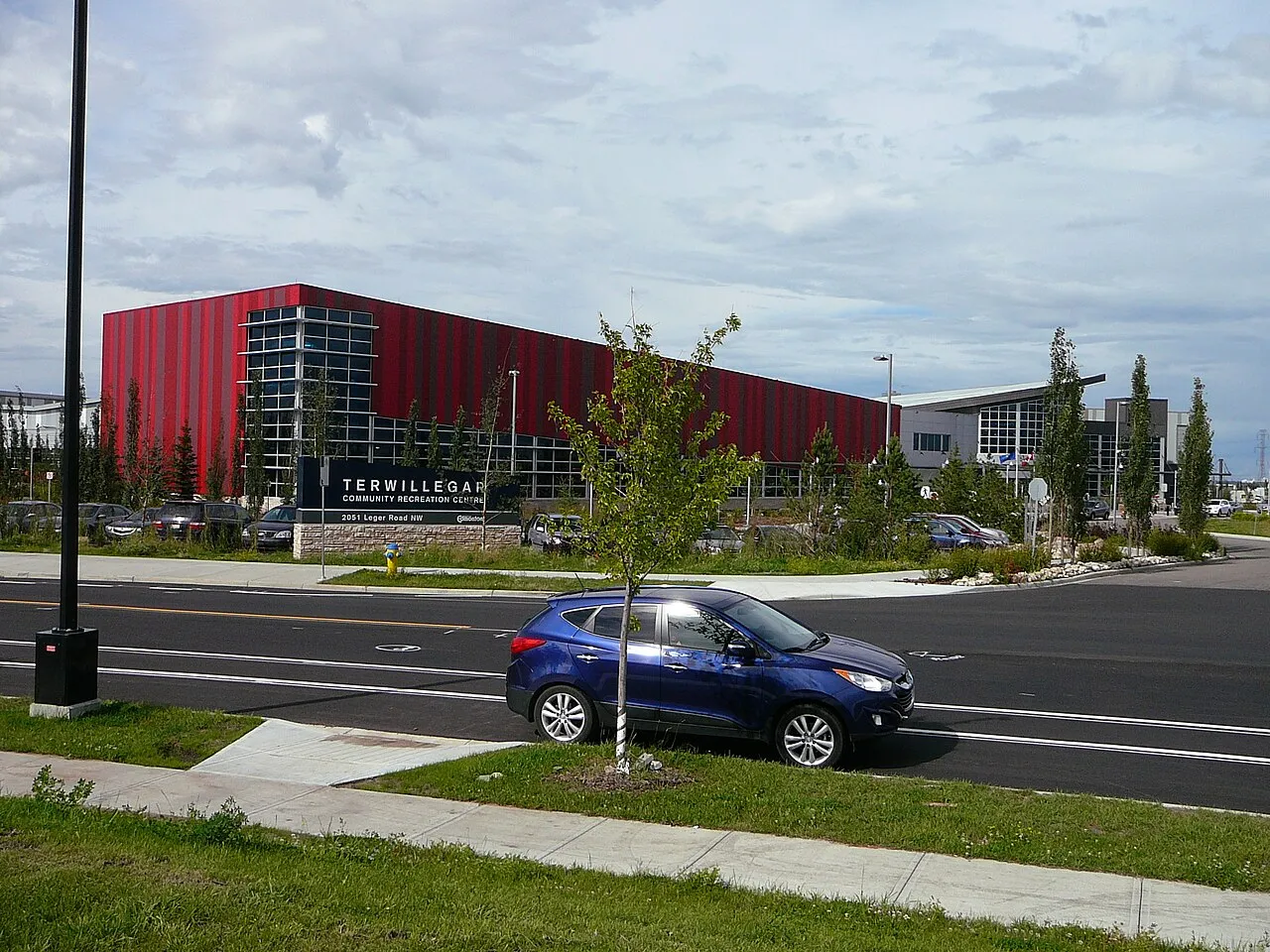 The Terwillegar Community Recreation Centre's red-panelled wing and glass-fronted addition, with its ground sign at 2051 Leger Road NW. — Terwillegar Arena