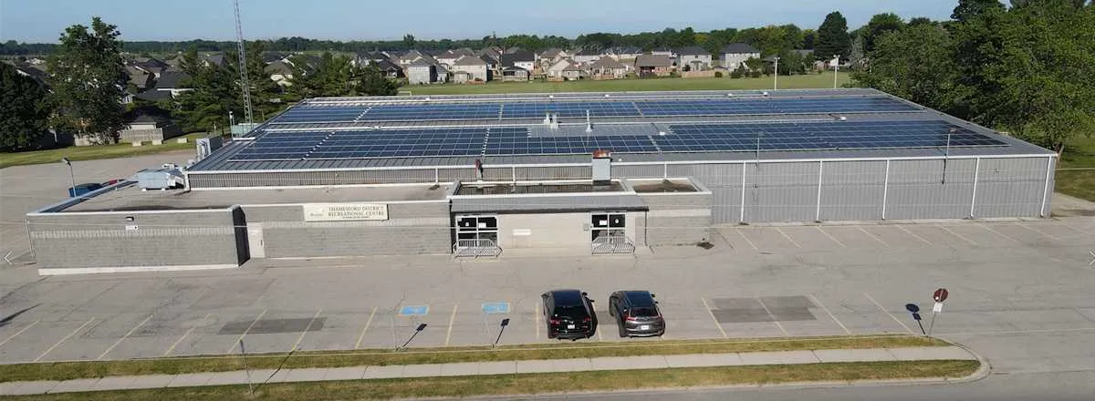 An aerial view of the Thamesford District Recreation Centre, its long roof covered in solar panels above the front parking lot. — Thamesford District Recreation Centre