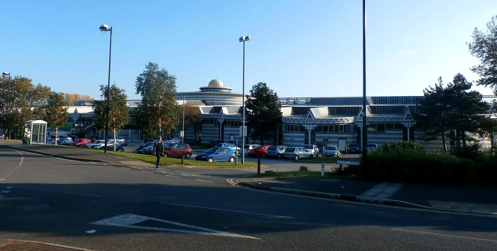 The Dome from Booth Avenue across its car park: a long, low grey-and-white striped building with gabled bays and a small gold dome above the centre (cropped). — The Dome Doncaster