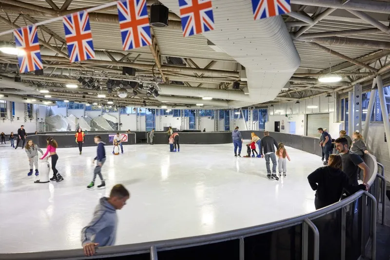 A wide view of the Doncaster Dome rink during a public session, skaters spread across the ice under strings of Union flags. — The Dome Doncaster
