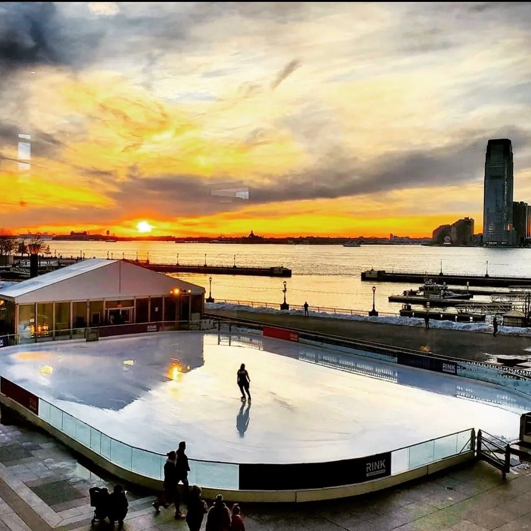 The Rink at Brookfield Place at sunset with a lone skater, the tent and the Hudson River behind — The Rink at Brookfield Place