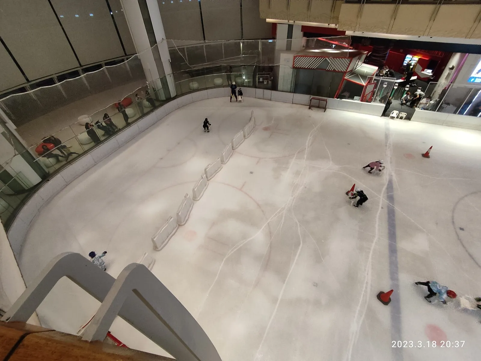 The ice at The Rink in Elements seen from the gallery above, with hockey markings, boards and a few skaters (March 2023). — The Rink (Elements)