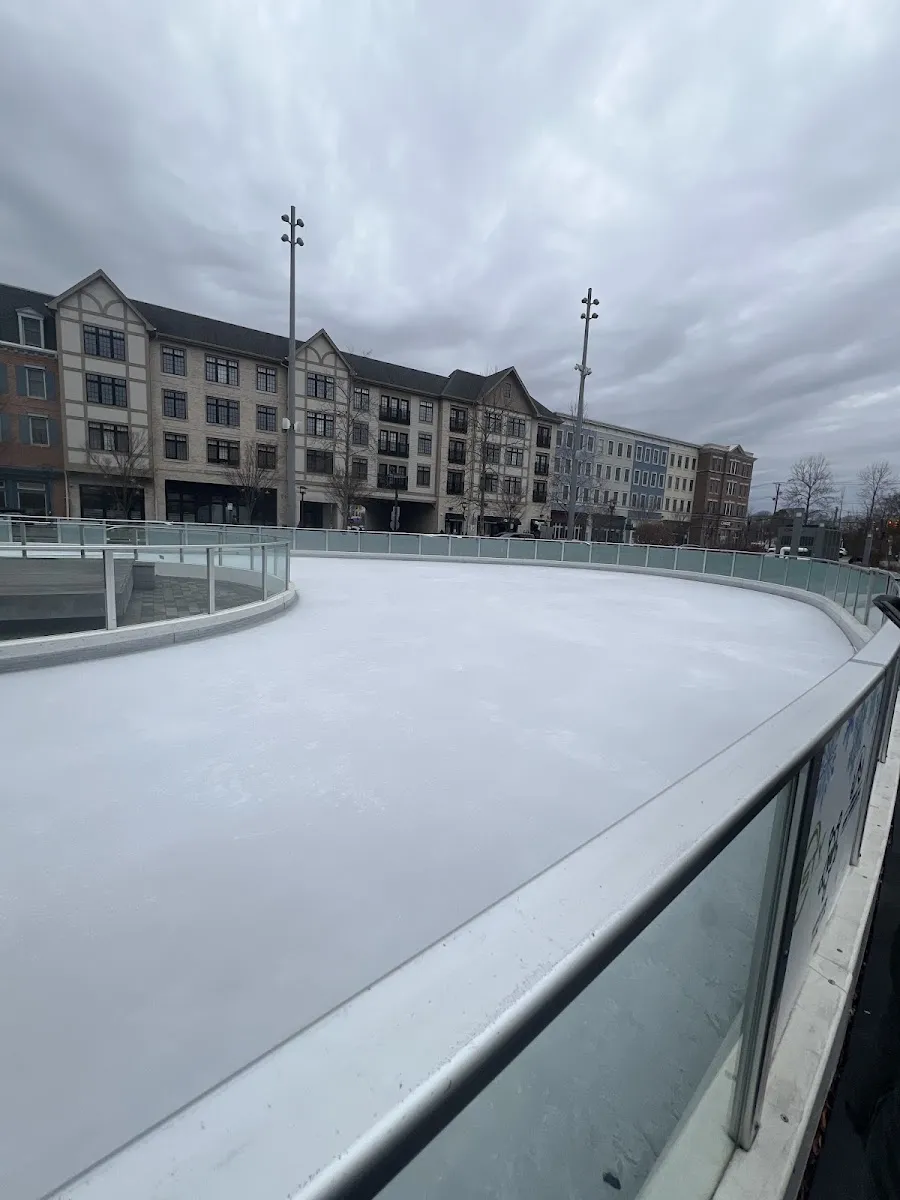 The empty ice of The Rinx at Wyandanch Plaza curving along a glass barrier with apartment buildings behind. — The Rinx at Wyandanch