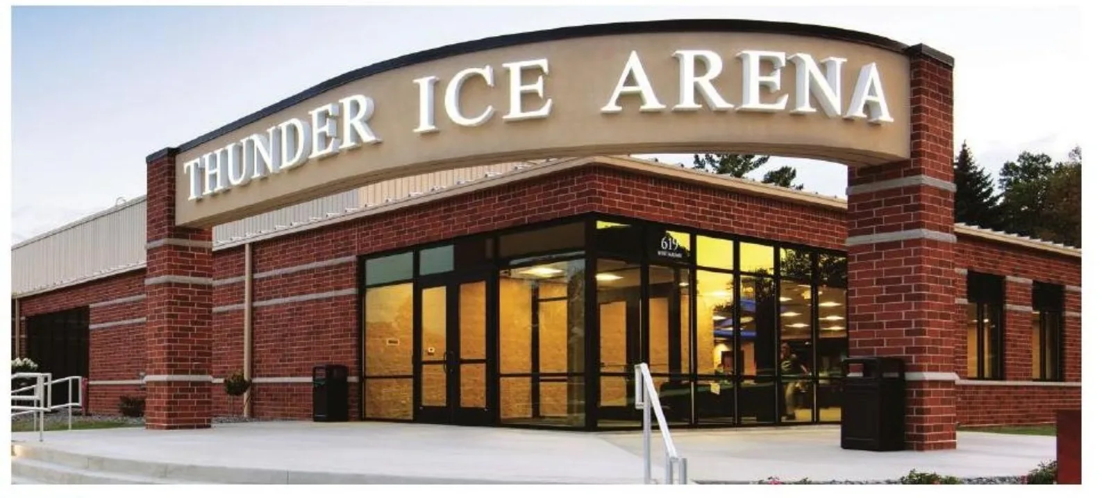 Entrada de ladrillo de Thunder Ice Arena con su letrero en arco de 'THUNDER ICE ARENA' y la dirección 619 West Maumee sobre las puertas de vidrio, fotografiada al atardecer. — Thunder Ice Arena (Angola)