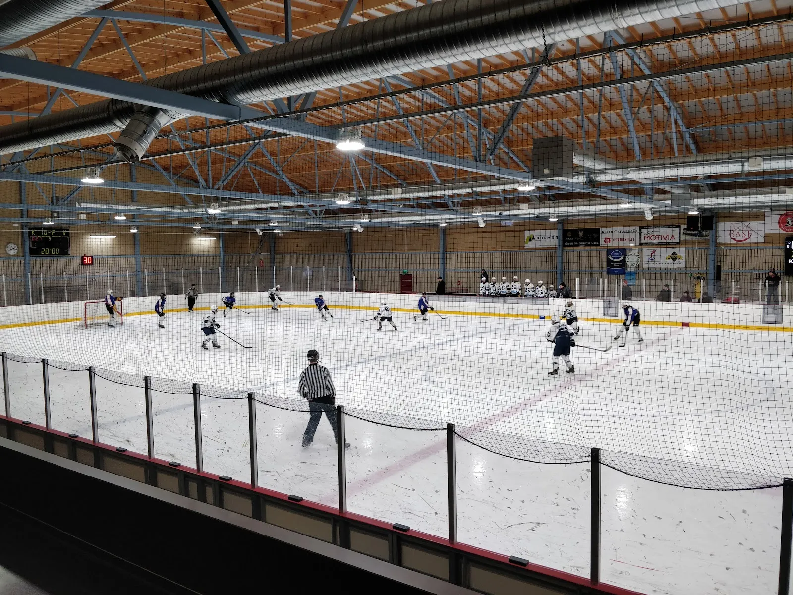 Tikkakosken jäähallin kenttä puisen kattonsa alla, kaukana kamerasta junioripeli – Tikkakosken jäähalli