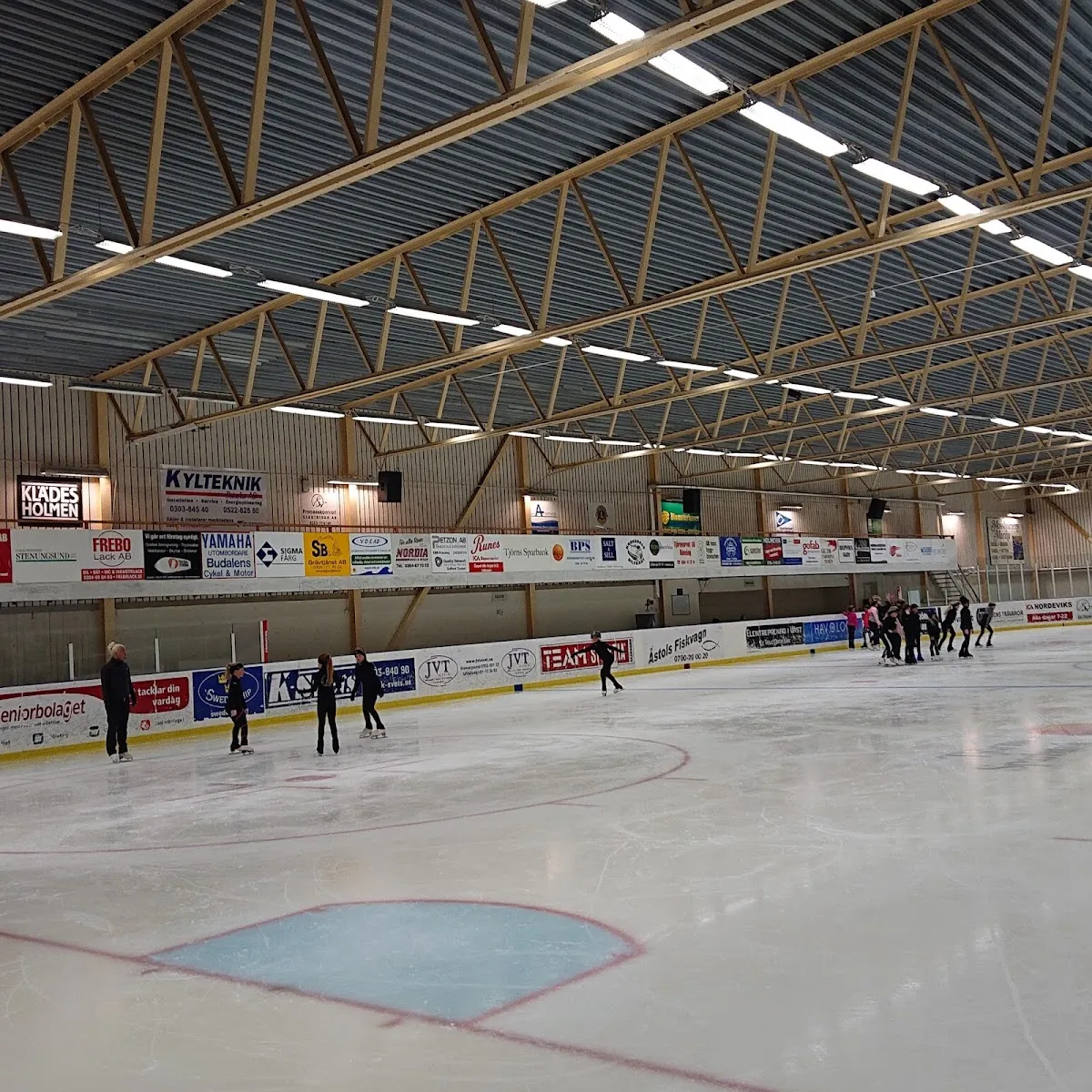 Skridskoåkare på isen i Tjörns ishall under ett åk med belysta läktare i bakgrunden – Tjörns ishall