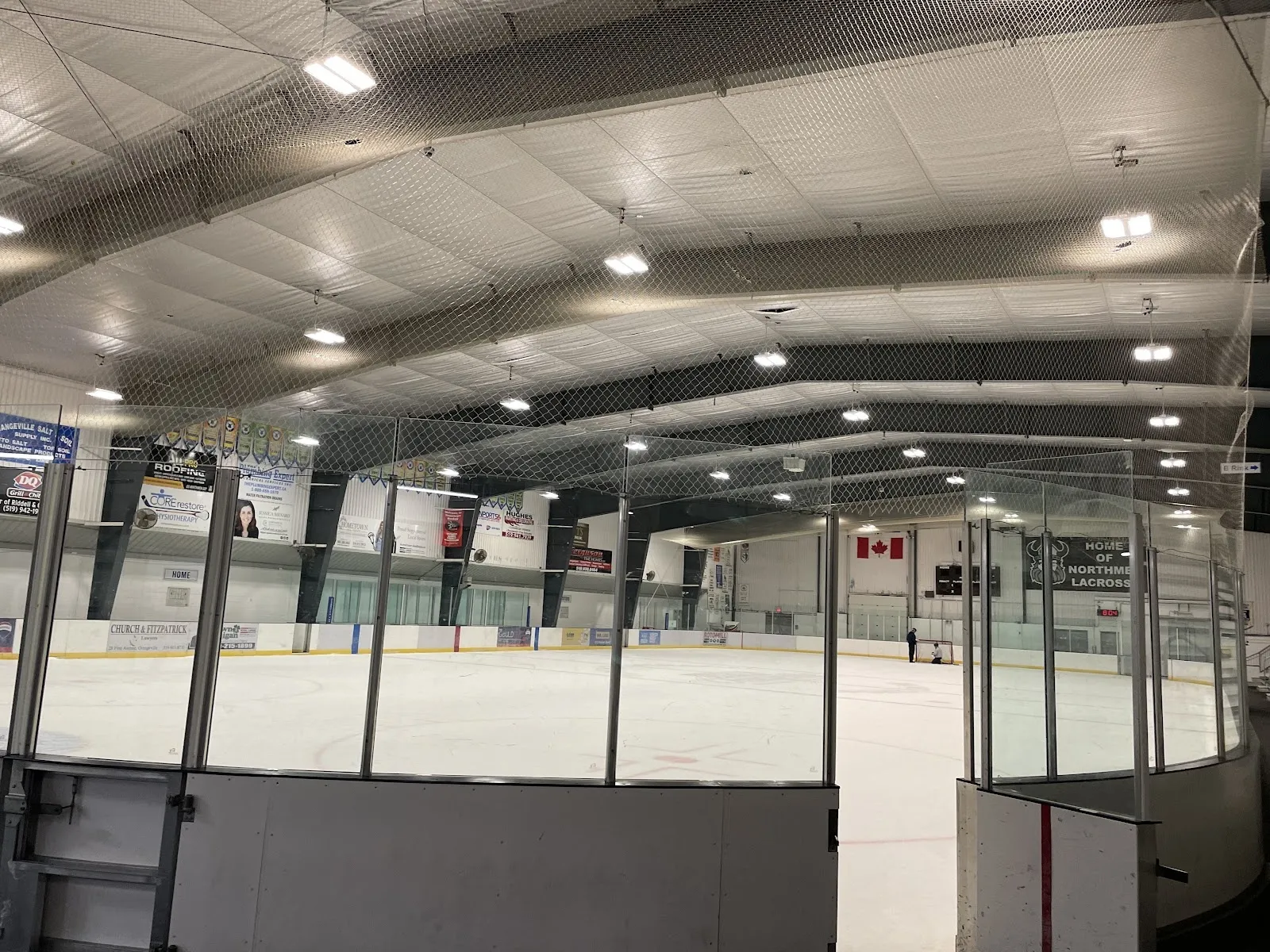 Una vista amplia de la pista a través del vidrio, una pista luminosa y vacía con una red a la izquierda y un techo de armaduras negras. — Tony Rose Memorial Sports Centre