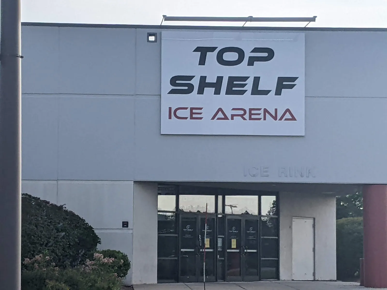 The grey Gurnee Mills facade with the Top Shelf Ice Arena sign above the glass entrance doors. — Top Shelf Ice Arena