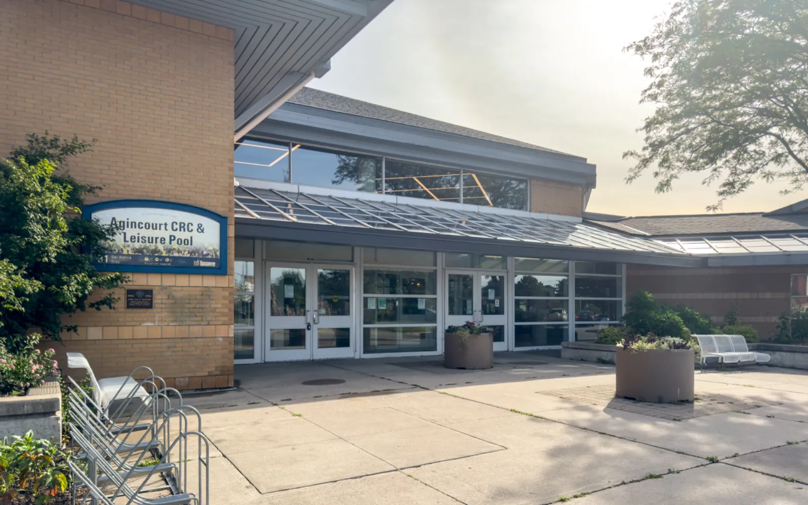 Front entrance of the recreation centre, brick facade with a lit sign reading 'Agincourt CRC & Leisure Pool', glass doors and canopy over the plaza. — Agincourt Community Recreation Centre