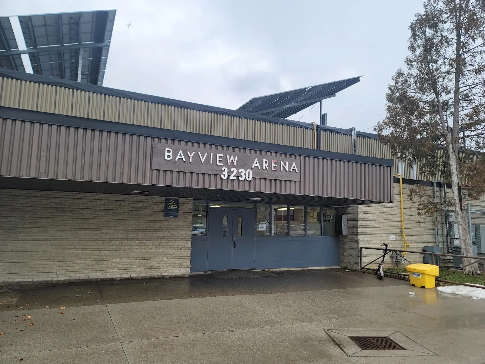 The entrance of the Bayview Arena at 3230 Bayview Avenue in Toronto, with its name sign and solar panels on the roof — Bayview Arena