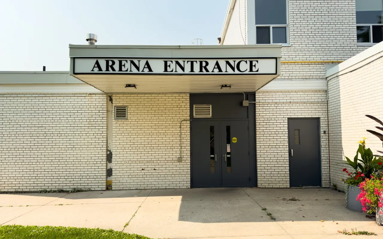 Arena entrance at Grandravine Community Recreation Centre, a pale patterned-brick wall with black double doors under an ARENA ENTRANCE sign. — Grandravine Community Recreation Centre