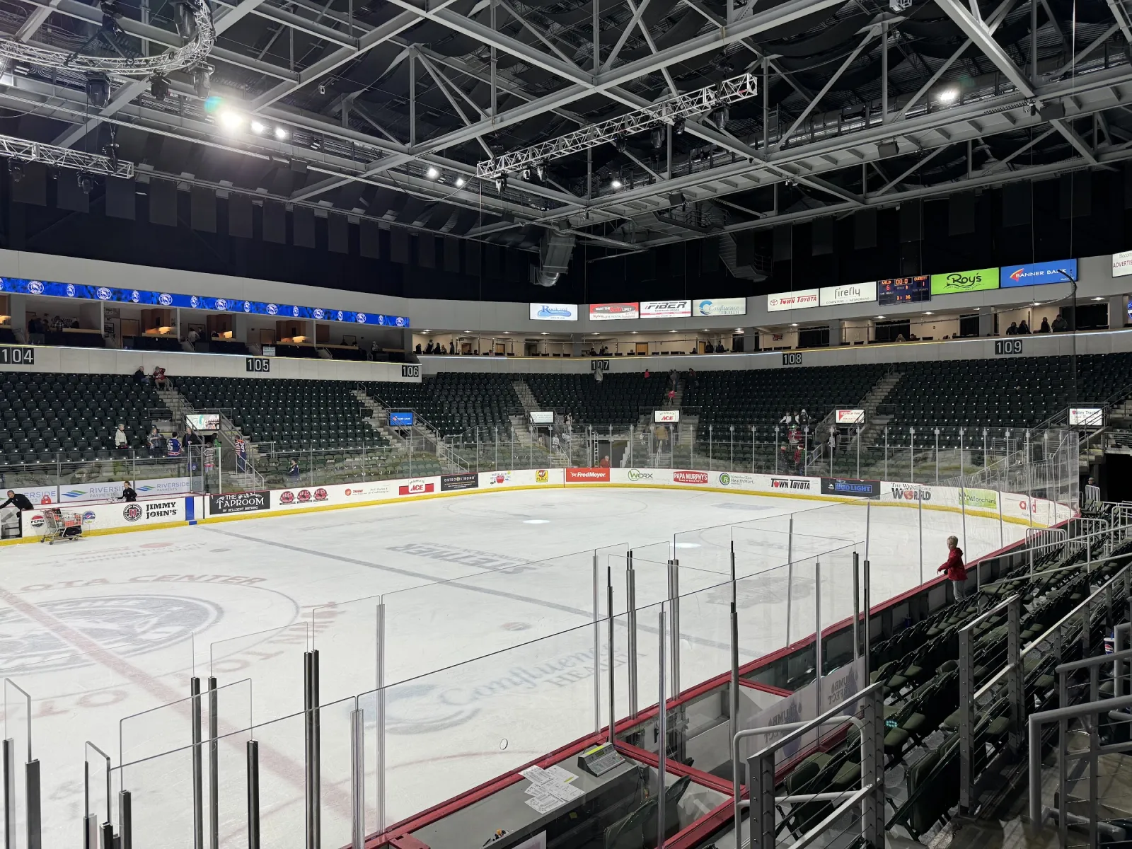 The main arena bowl from the lower seats: the ice with its centre logo, the glass, and tiers of seats and suites under a black steel roof. — Town Toyota Center