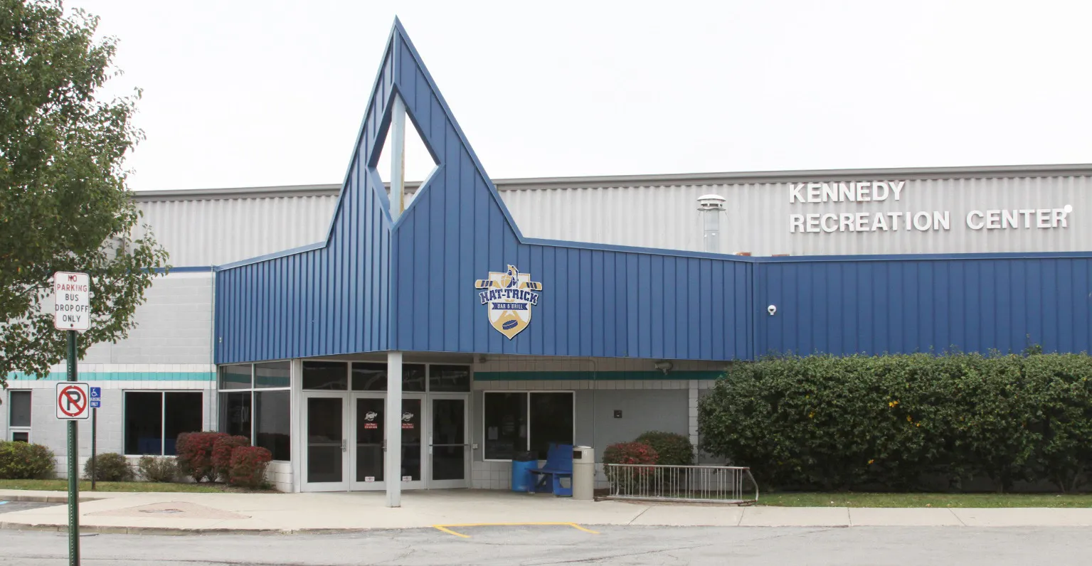 The Kennedy Recreation Center entrance in Trenton: the blue peaked canopy over the glass doors, with the center's name on the rink wall behind — Trenton Kennedy Recreation Center