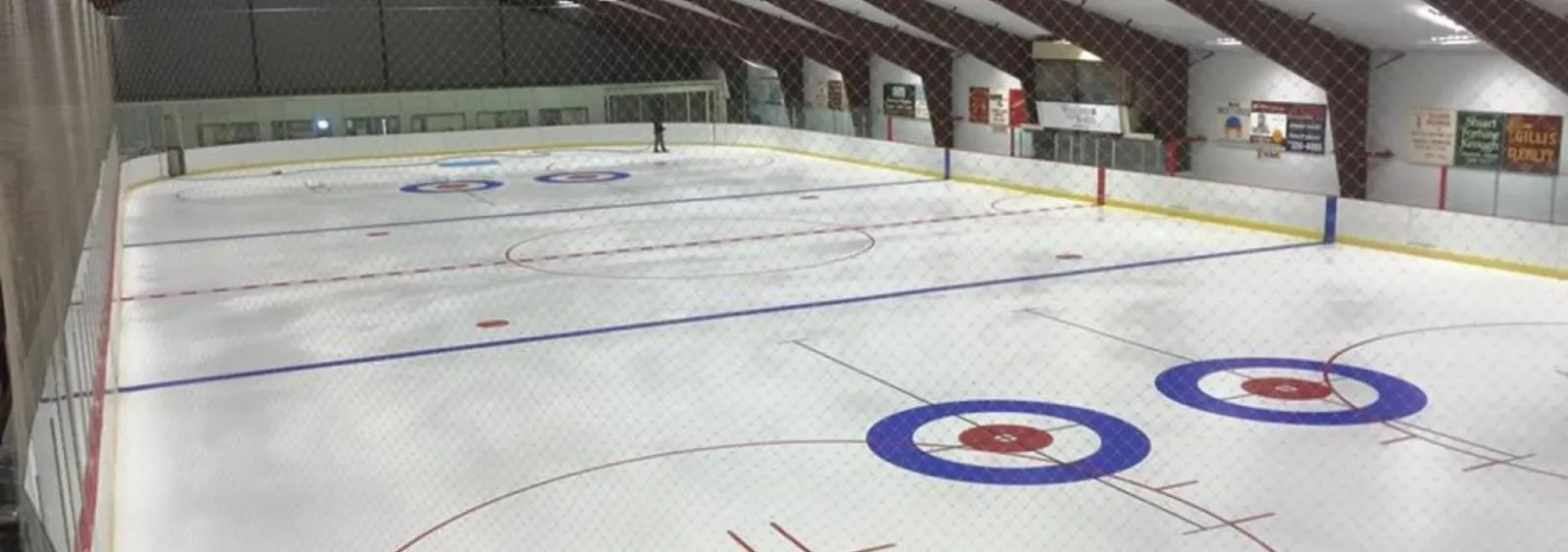 A wide view of the Tupper Lake Civic Center ice with painted circles at centre, the netting and boards along the far side. — Tupper Lake Memorial Civic Center