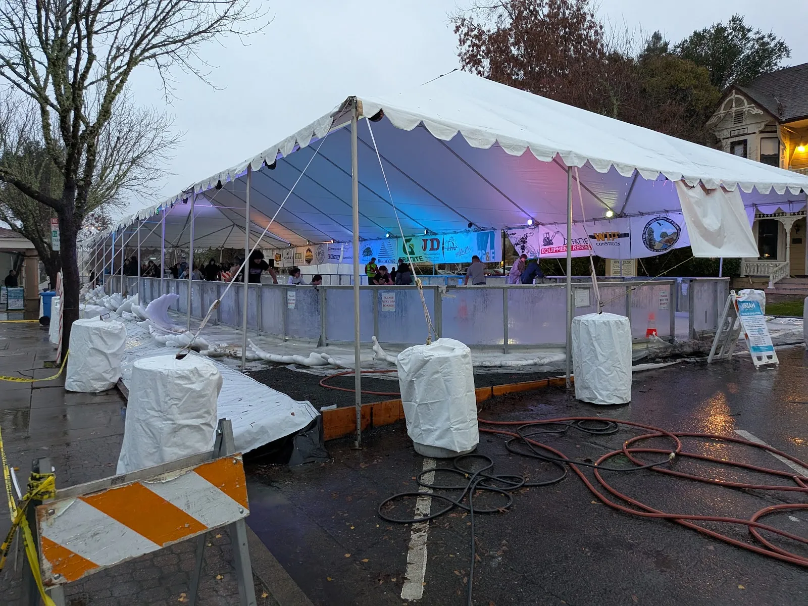 The tented Ukiah on Ice rink in the plaza on a rainy day, with its boards and ice-chiller hoses — Ukiah on Ice