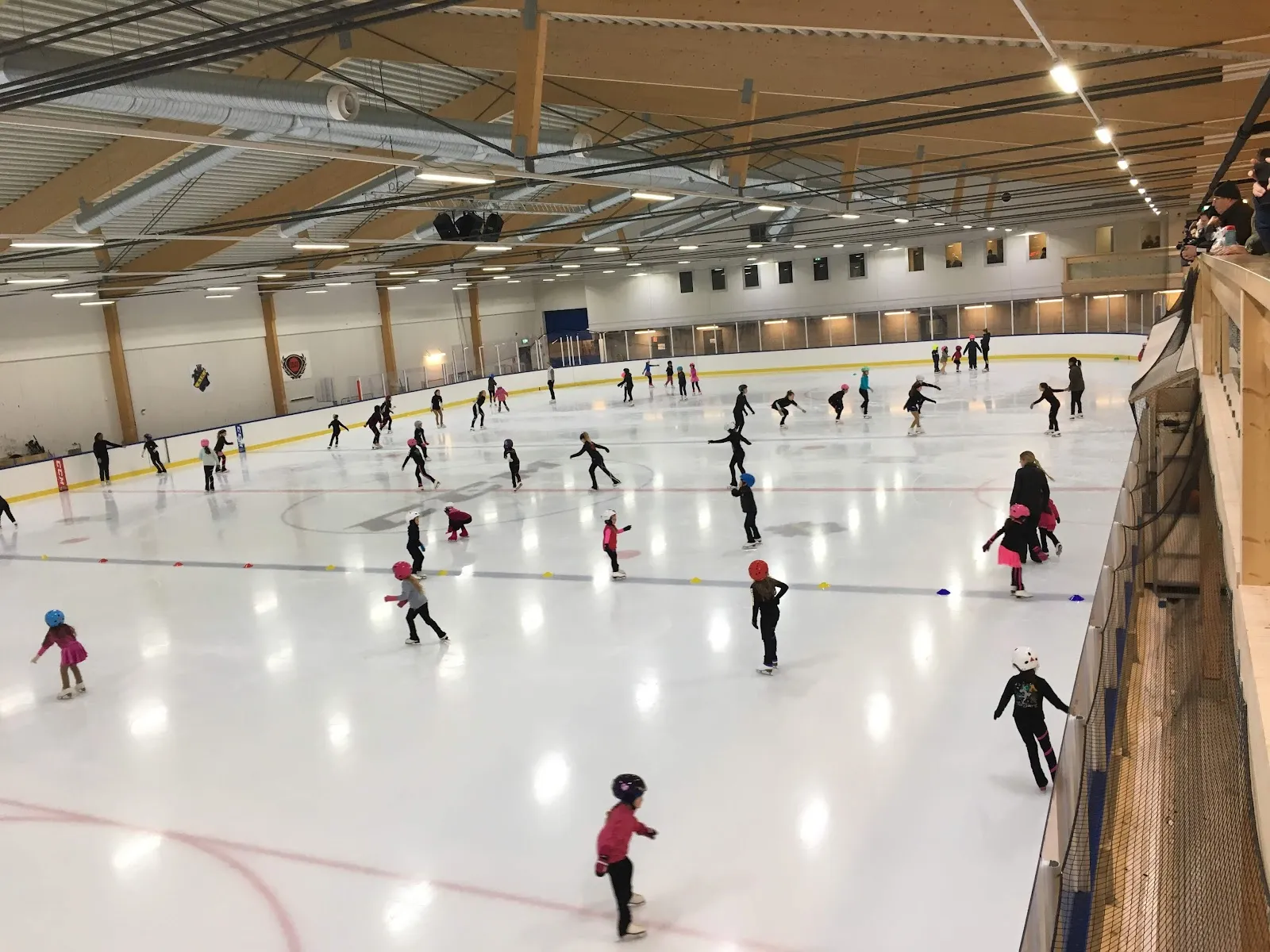 Children skating on the ice sheet of the hall at Ulriksdals idrottsplats in Solna, seen from the upper gallery – Ulriksdals IP, Ishall 2 (Solna)