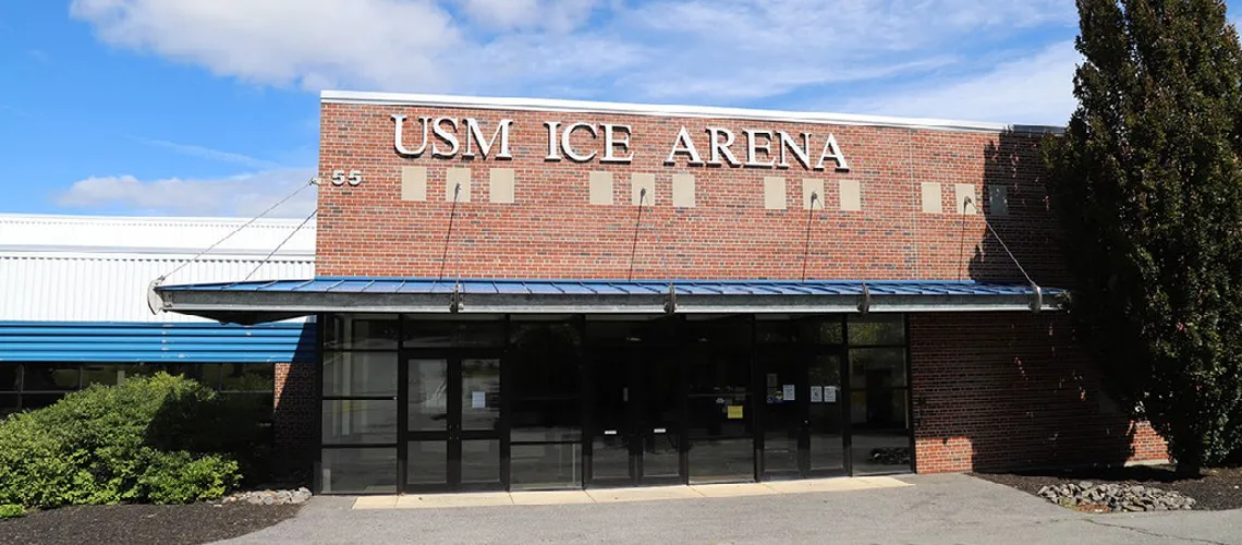 The brick front of the USM Ice Arena on Campus Avenue in Gorham with the building number 55 beside the entrance canopy — USM Ice Arena