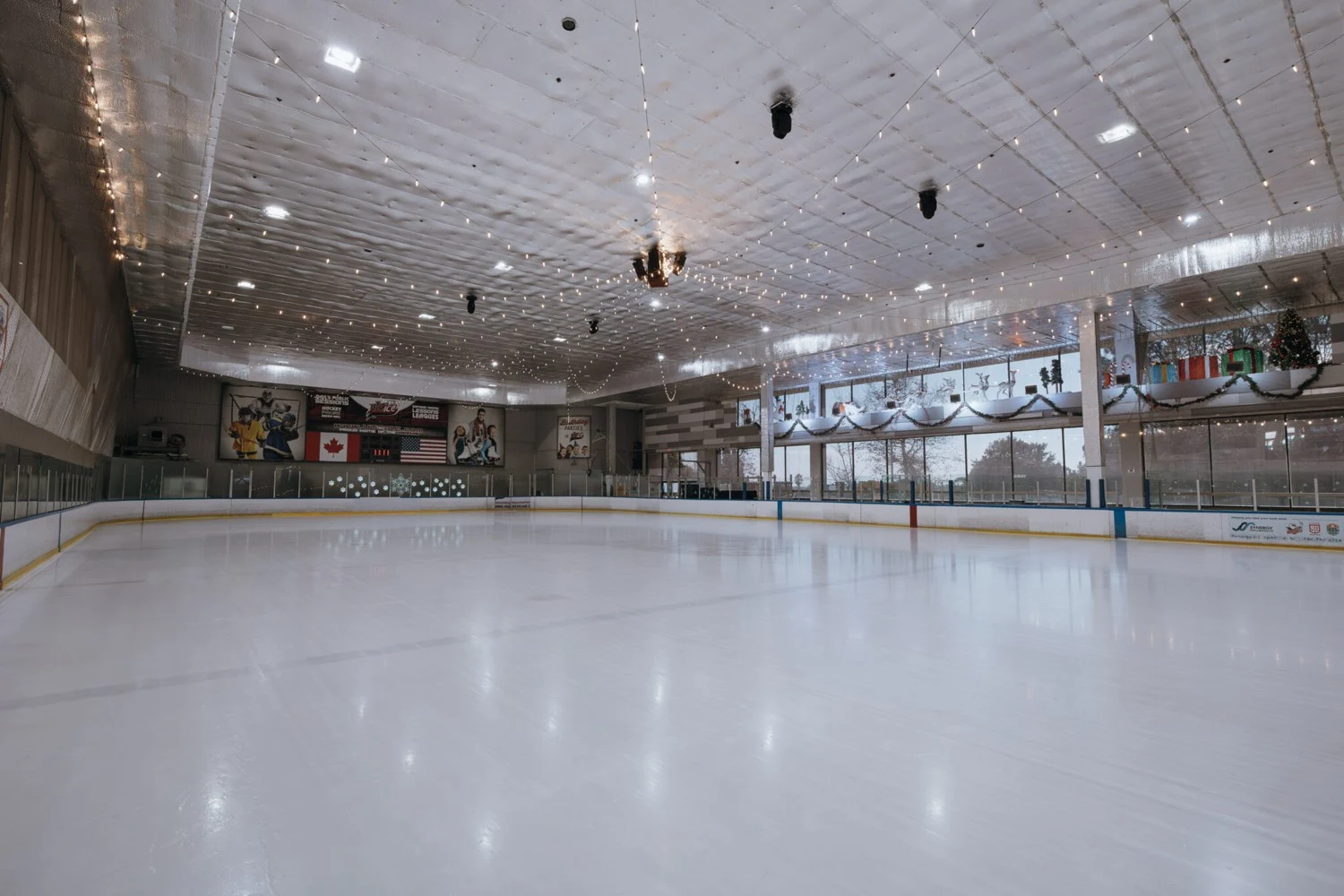 UTC Ice’s rink beneath holiday decorations, with the mall windows along one side. — UTC Ice Sports Center