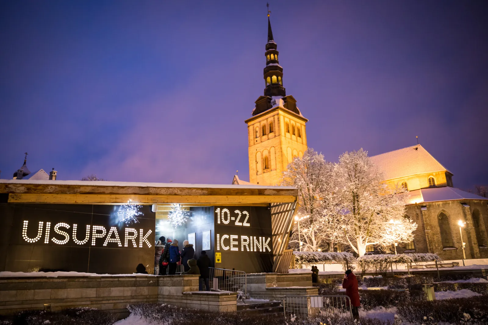 The Old Town rink's entrance hoarding with the UISUPARK ICE RINK sign, with the spire of St Nicholas' Church behind it. — Vanalinna uisupark