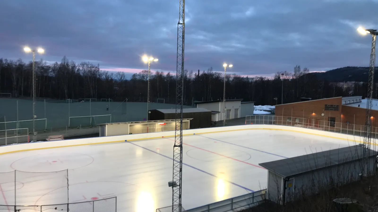 Den upplysta utomhusrinken vid Vapenvallen i Huskvarna i skymningen – Vapenvallen isbana