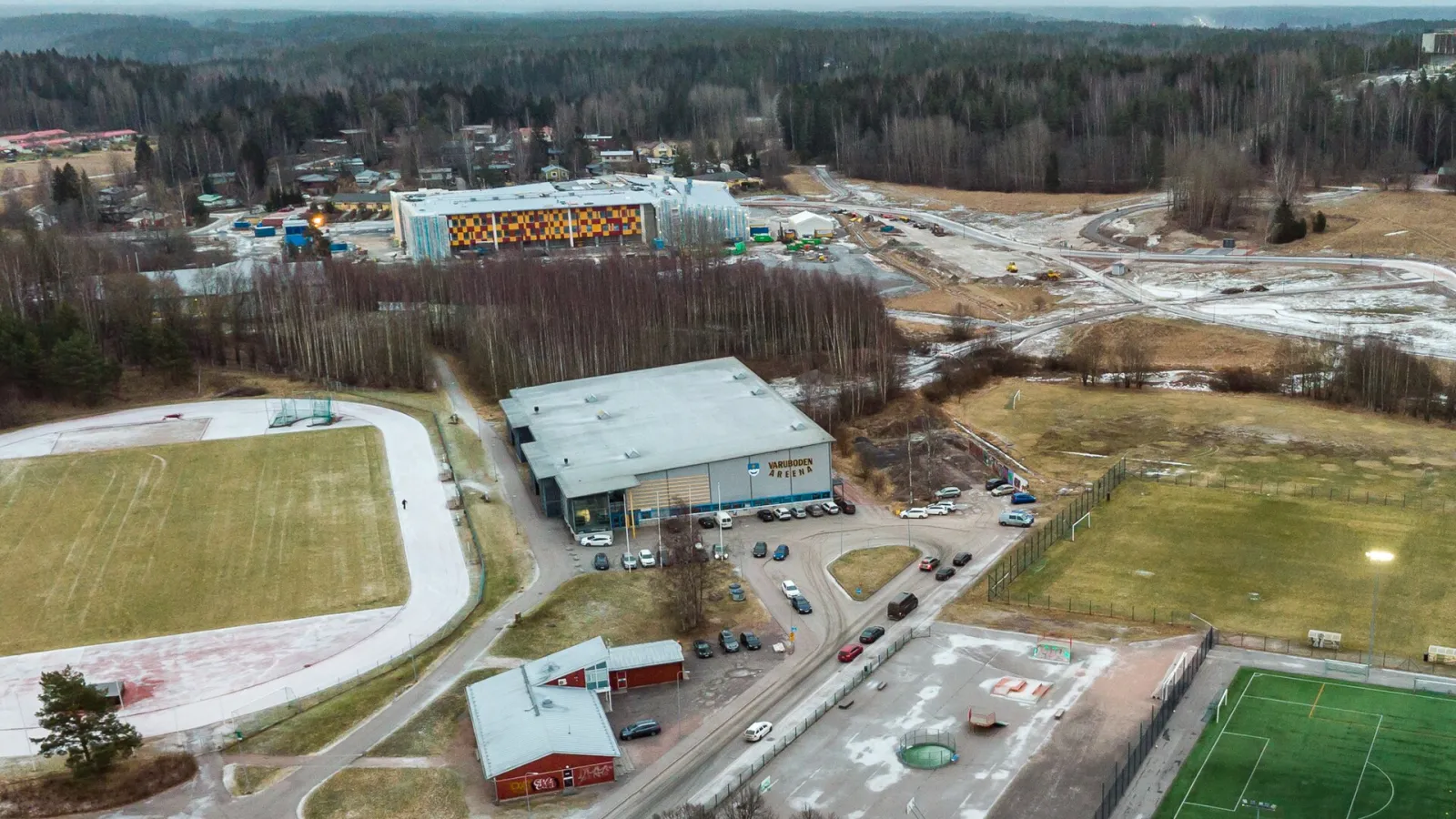 Varuboden Areena in Kirkkonummi seen from above, the hall with its name sign above the car park beside the sports park — Varuboden Areena