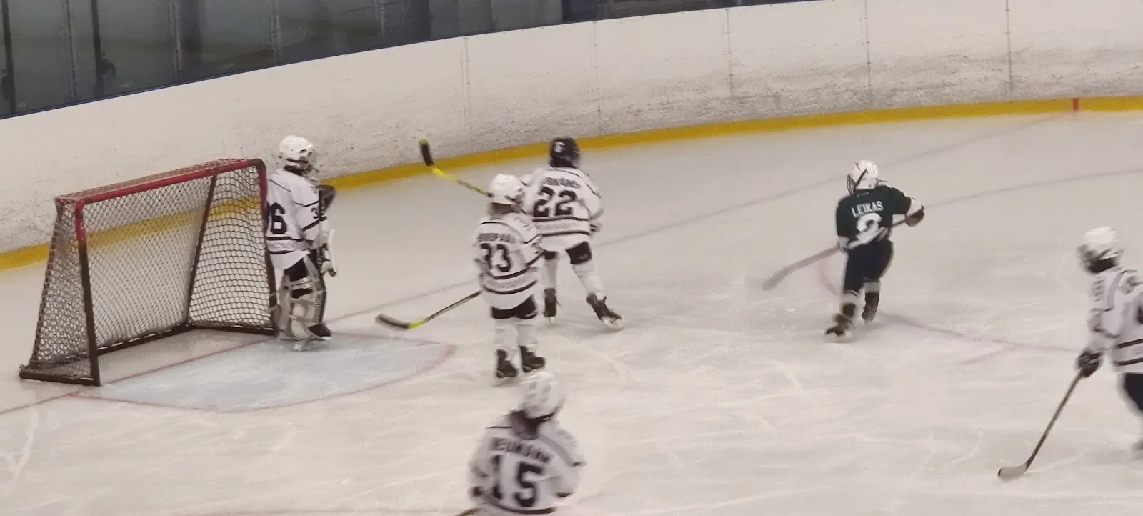 Young players at a goal on the ice of Varuboden Areena in Kirkkonummi, with the glass and the sponsor boards behind them. — Varuboden Areena