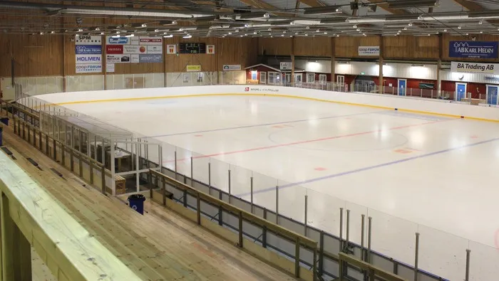 The empty ice surface of the Vasavallens ishall in Strängnäs seen from behind the boards, with the stands along the long side. — Vasavallens ishall