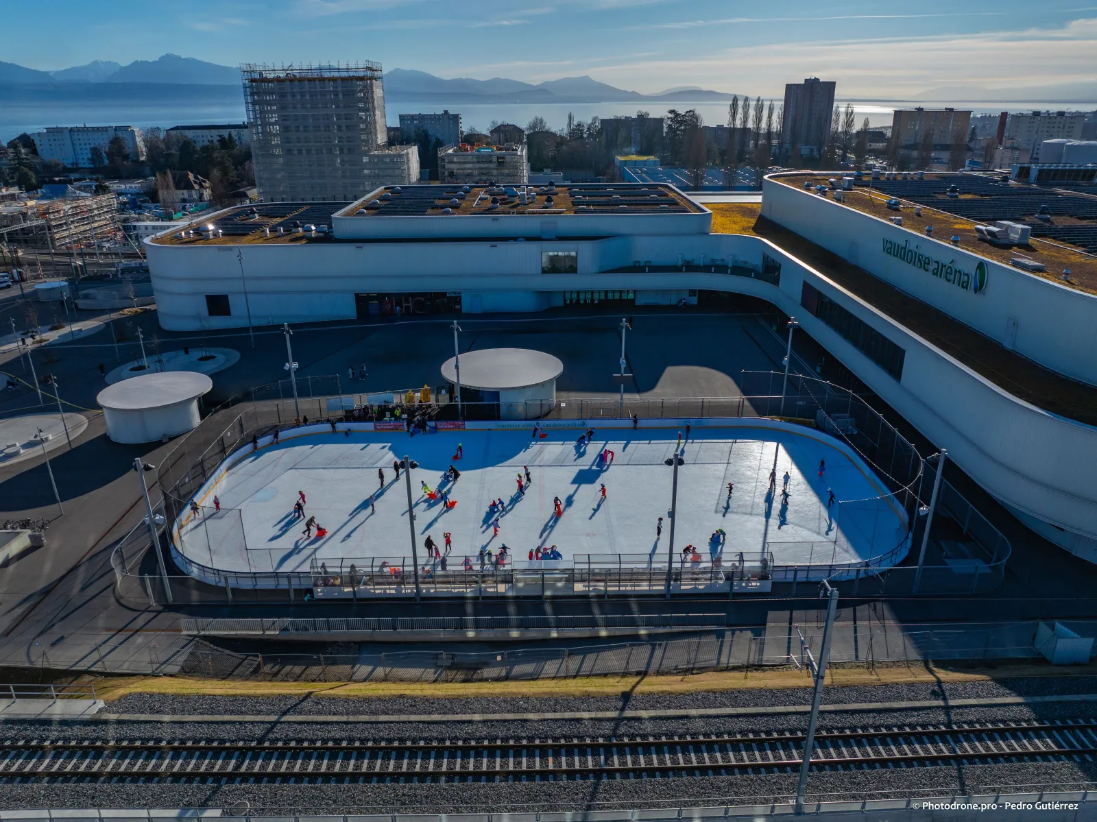 The Vaudoise aréna from above, with the outdoor rink in front of its curved wall and Lake Geneva beyond — Vaudoise aréna (patinoires)