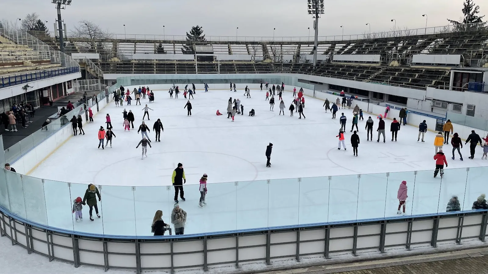 Otvoreno klizalište sportsko-rekreacijskog centra Šalata u Zagrebu, s klizačima na ledu i betonskom tribinom uz rub. — Video-disco klizalište Šalata