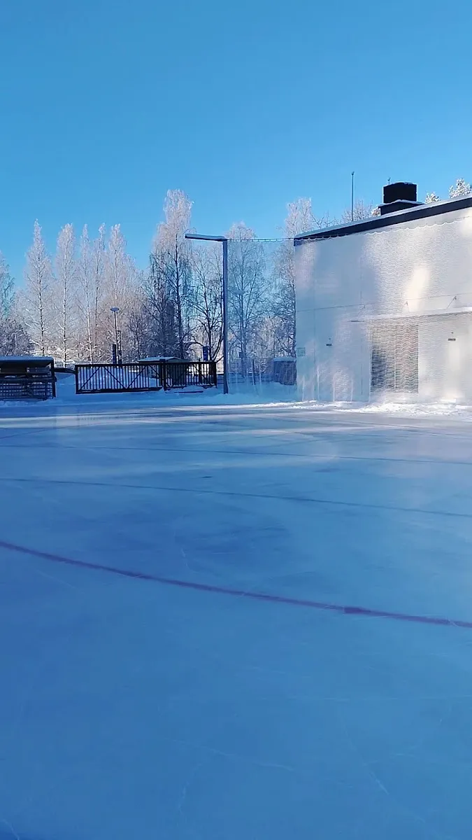The outdoor artificial ice at Viitaniemi in Jyväskylä beside the white service building, in low winter light — Viitaniemen ulkotekojäärata