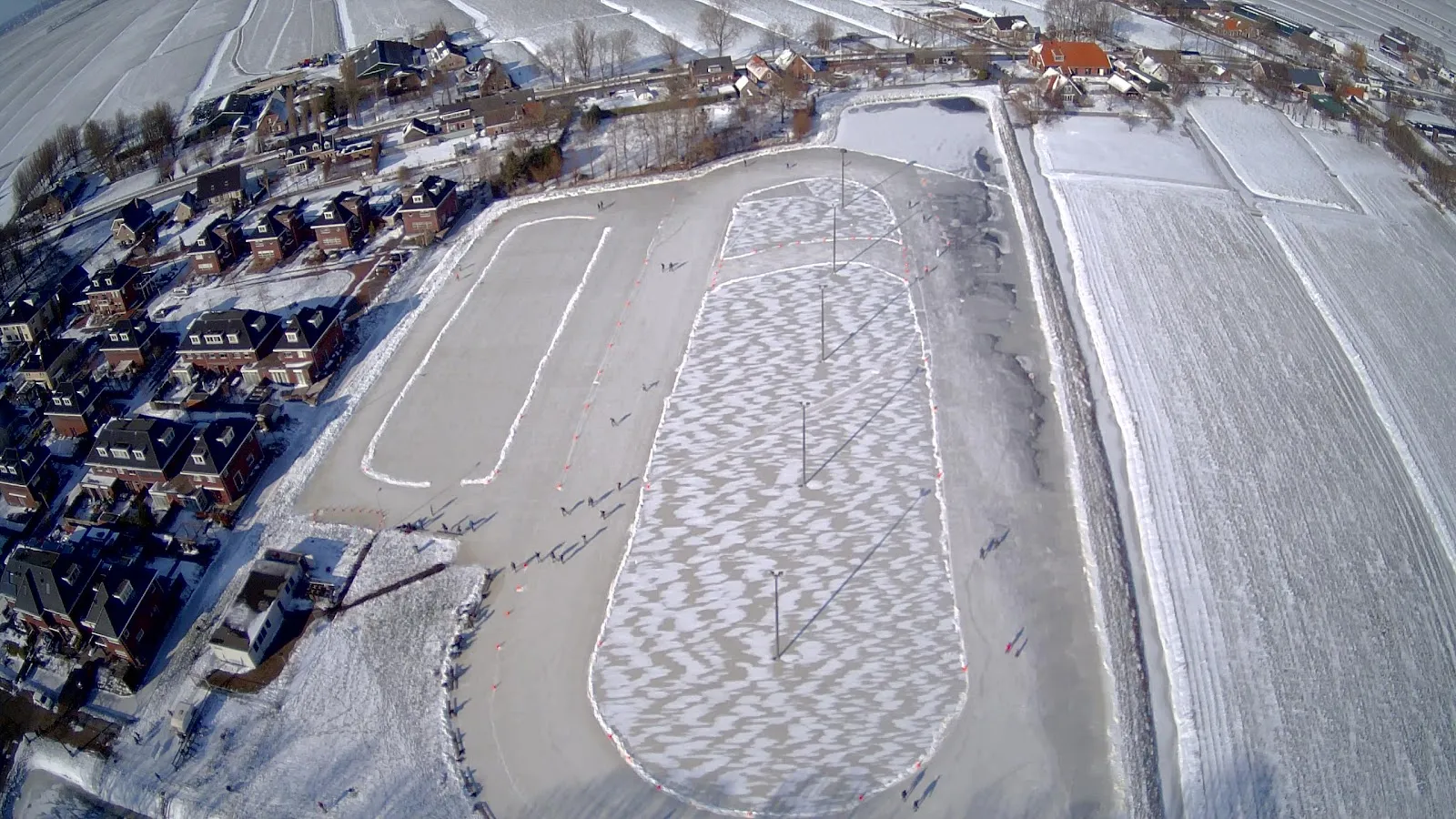 A bird's-eye view of the Koudekerk ice track with its patterned surface, snow banks and the stands along the side. — Landijsbaan Koudekerk aan den Rijn (VIJK)