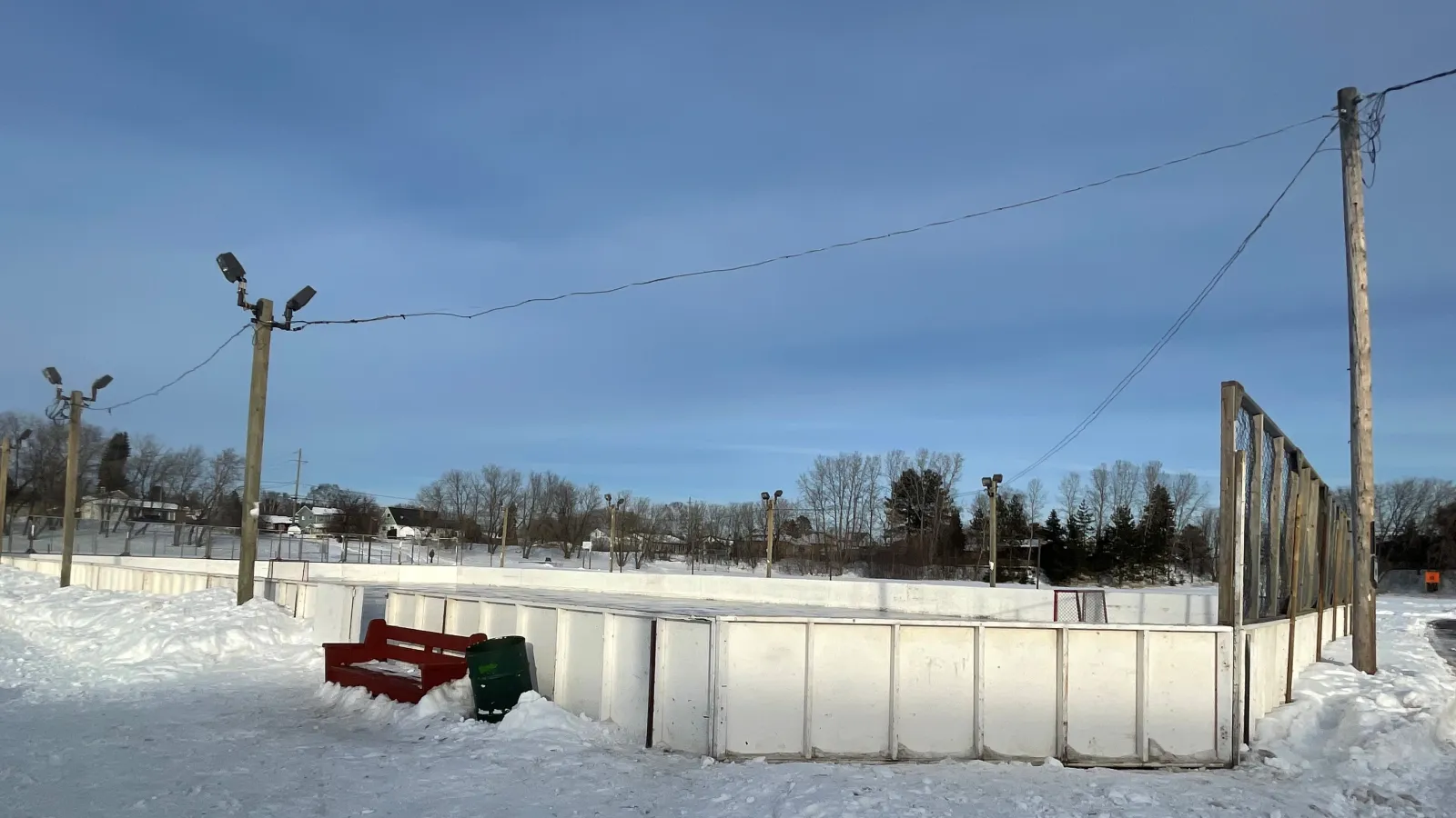 La pista con vallas de Waddington Park con una banca y un bote de basura junto a las vallas — Waddington Park Outdoor Rink