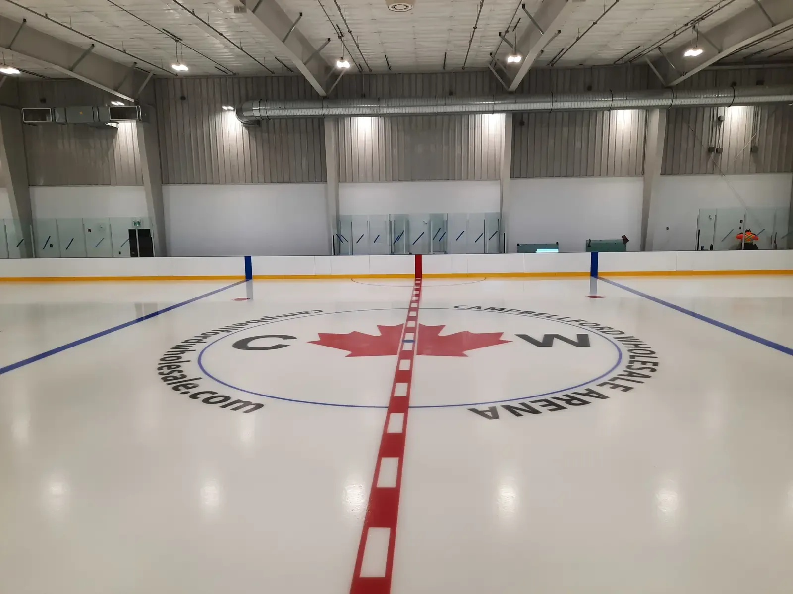 The ice surface at Warkworth Arena, with a maple-leaf logo at centre ice and glass above the boards. — Warkworth Arena