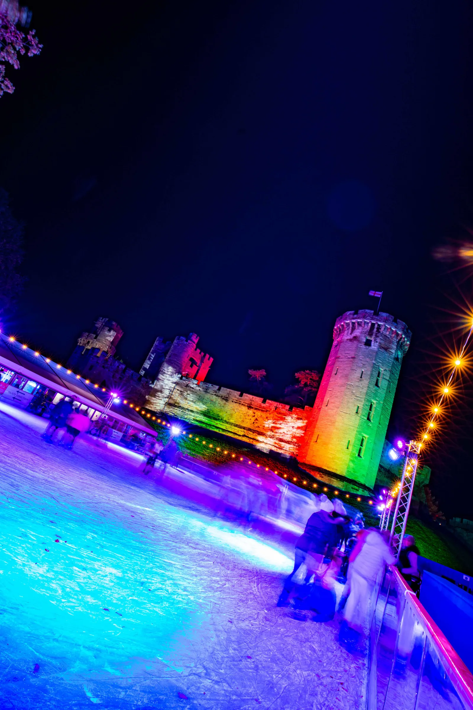 Skaters on the open-air ice with the castle lit behind — Warwick Castle Ice Rink