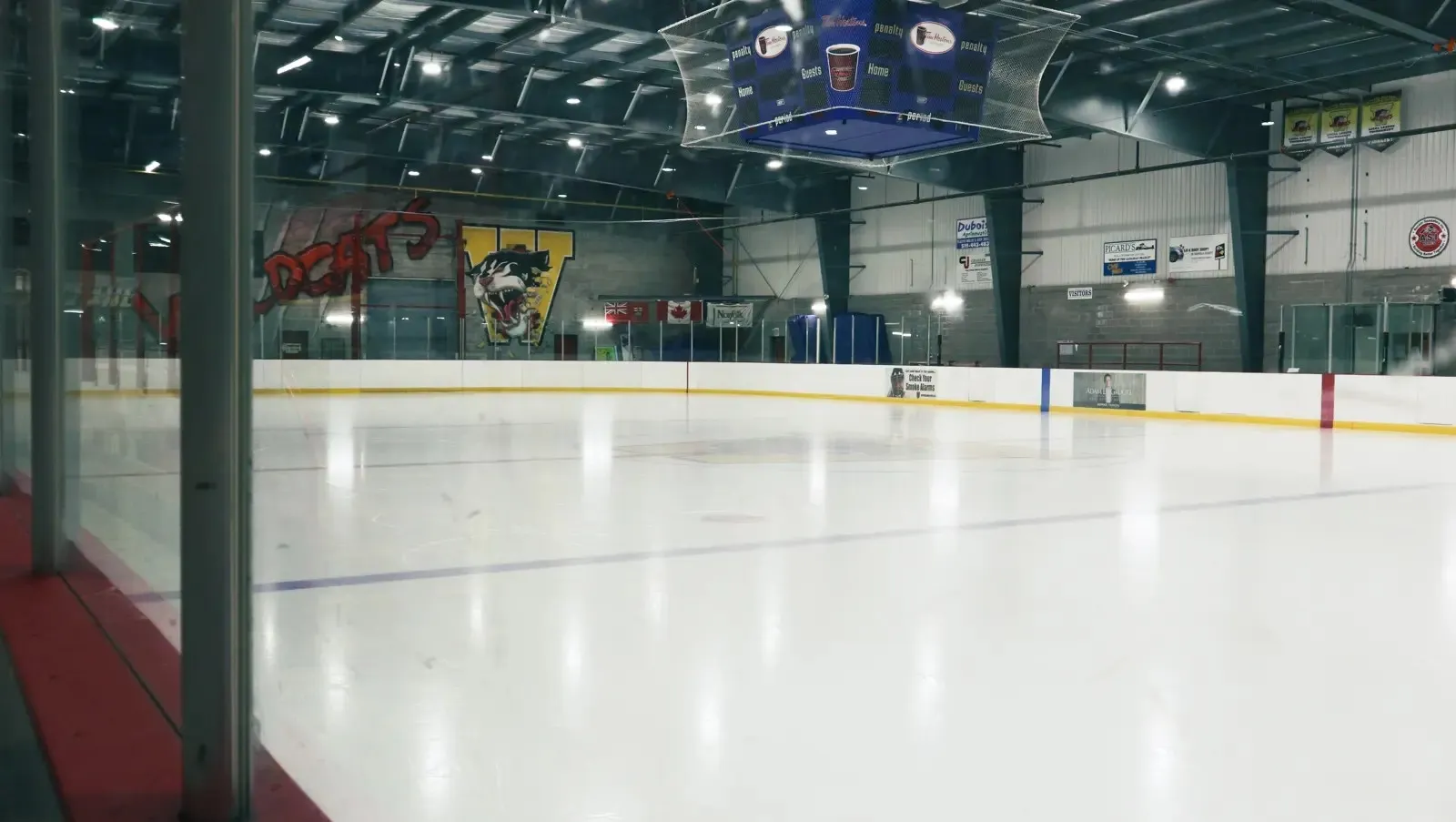 The ice at the Waterford Tricenturena seen from behind the glass, with the boards and bench area at the side of the rink — Waterford Tricenturena