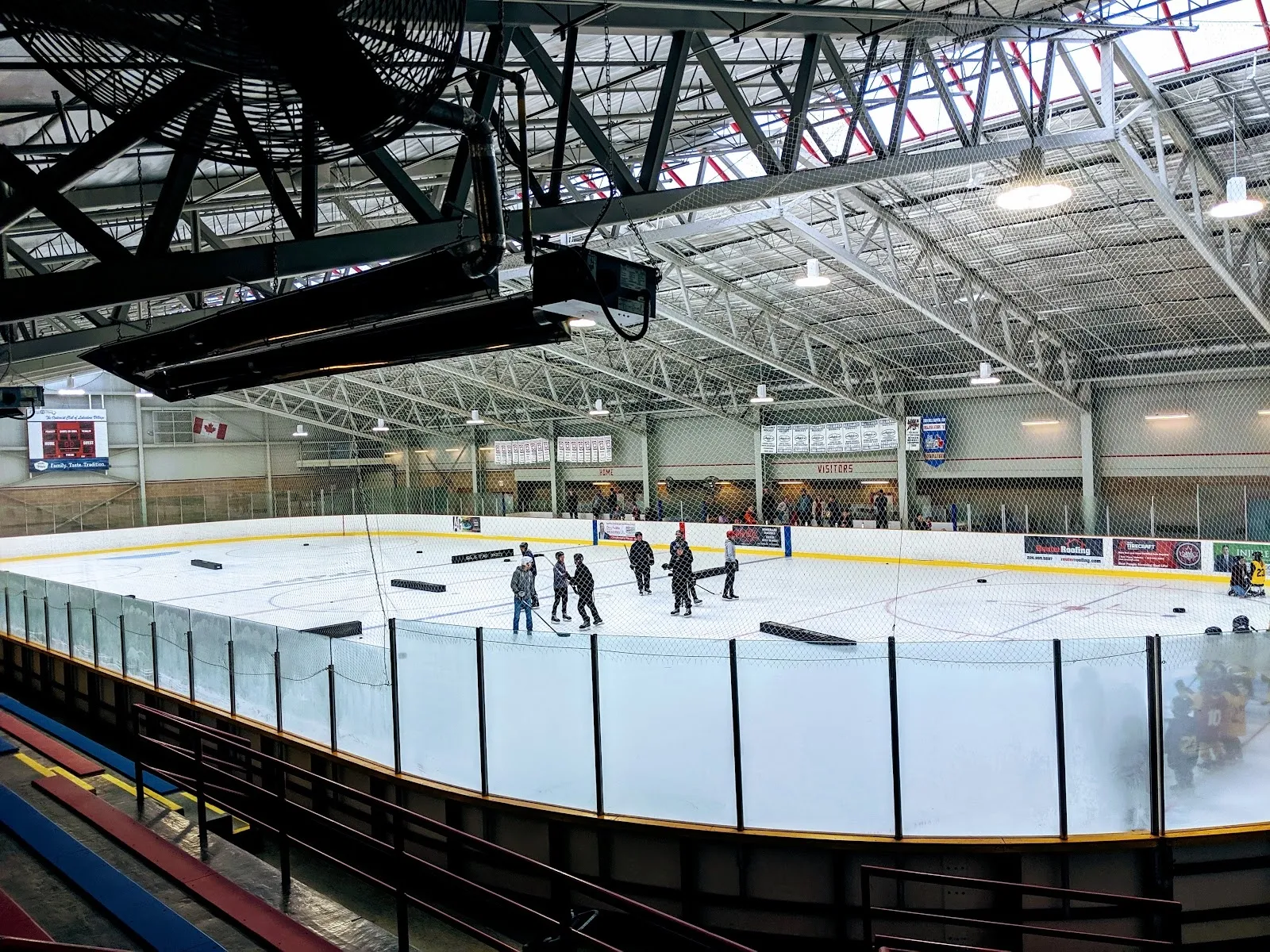 Una pista amplia vista desde detrás de las vallas con unos cuantos jugadores cerca del extremo opuesto, con vigas de acero y una larga pared de vidrio arriba. — Albert McCormick Community Centre