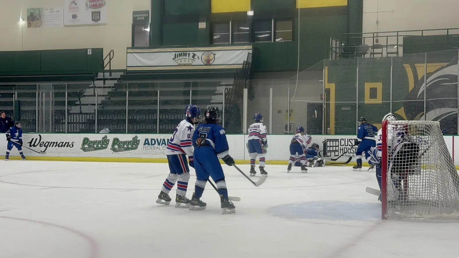A youth hockey game on the arena ice, seen from beyond the boards — Wegmans Ice Arena (SUNY Brockport)