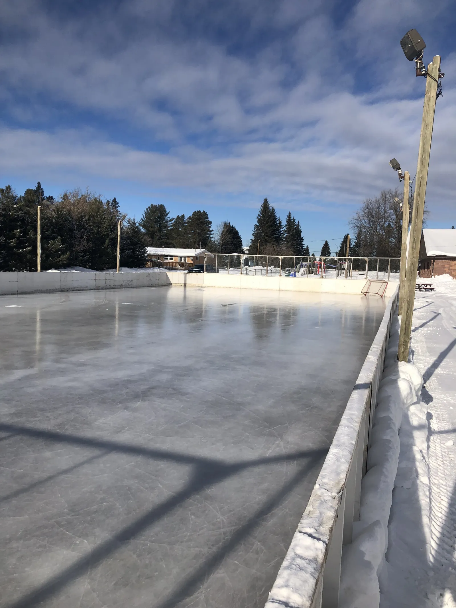 The boarded rink at West Arthur Community Centre with a clear sheet of ice and floodlight poles — West Arthur Community Centre Outdoor Rink