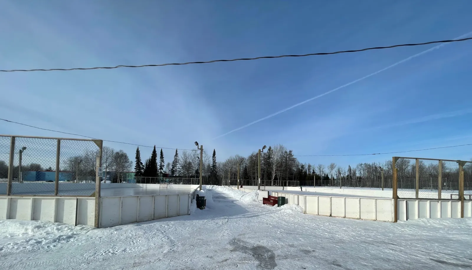 La pista con vallas de West End Park iluminada de noche, vista desde arriba, con patinadores en el hielo — West End Park Outdoor Rinks
