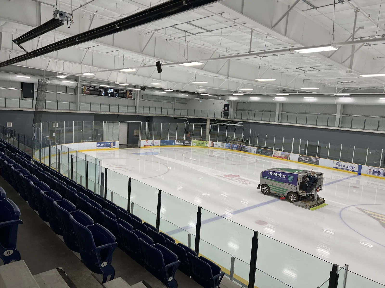 The Zamboni resurfacing the arena ice at West Lincoln Community Centre, with seating along the side. — West Lincoln Community Centre