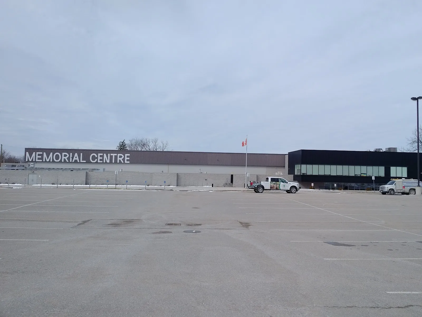 The long low West Middlesex Memorial Centre building with MEMORIAL CENTRE lettered across its wall, seen from across an empty parking lot under a grey sky. — West Middlesex Memorial Centre (Strathroy)