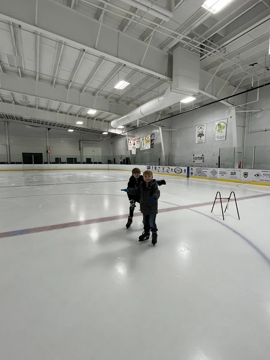 The indoor ice sheet at West Shore Community Ice Arena with two skaters in the middle distance — West Shore Community College Ice Arena