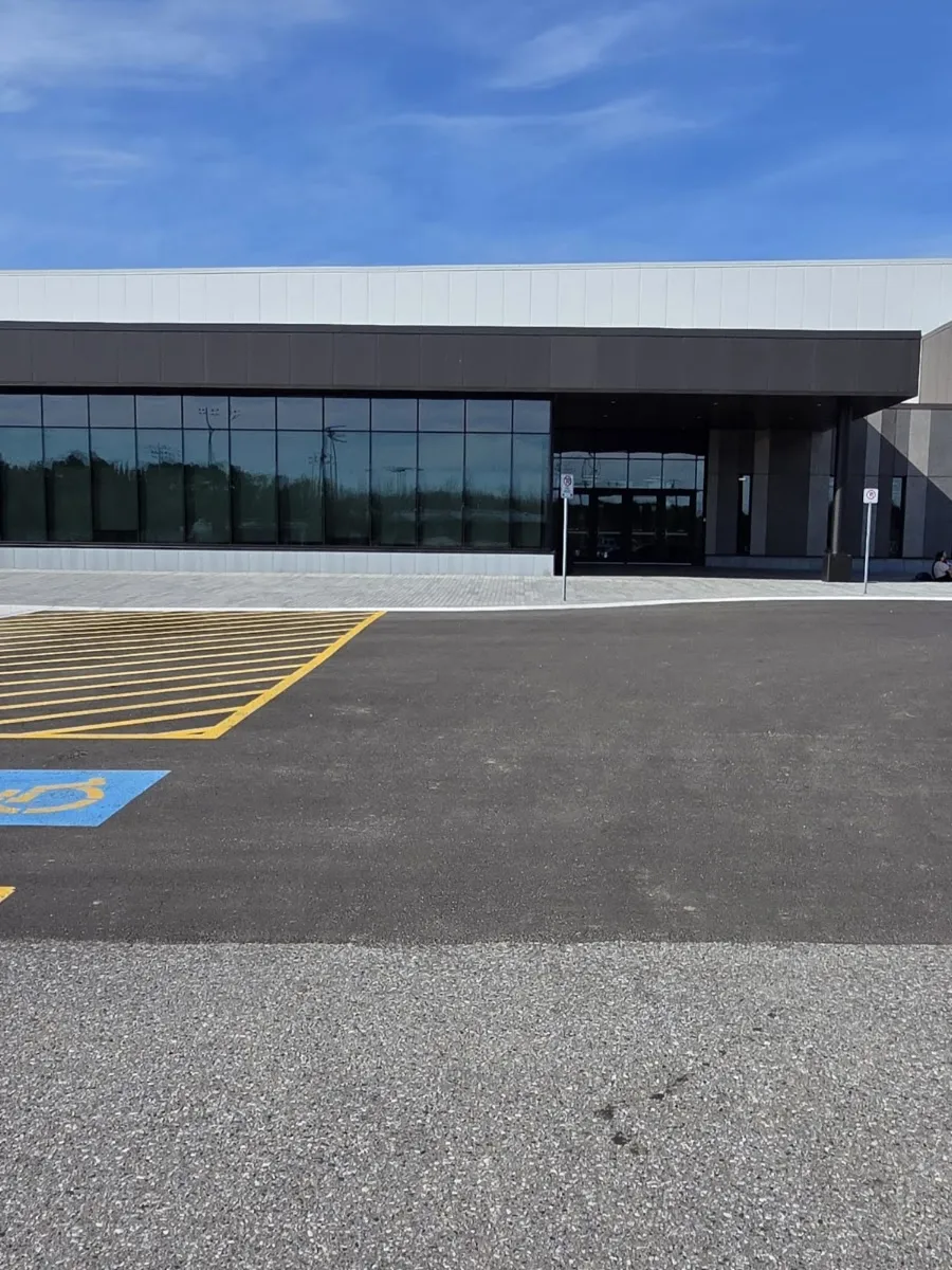 The glass and dark-panelled entrance of the new WFCU Place across its parking lot. — WFCU Place (North Bay)