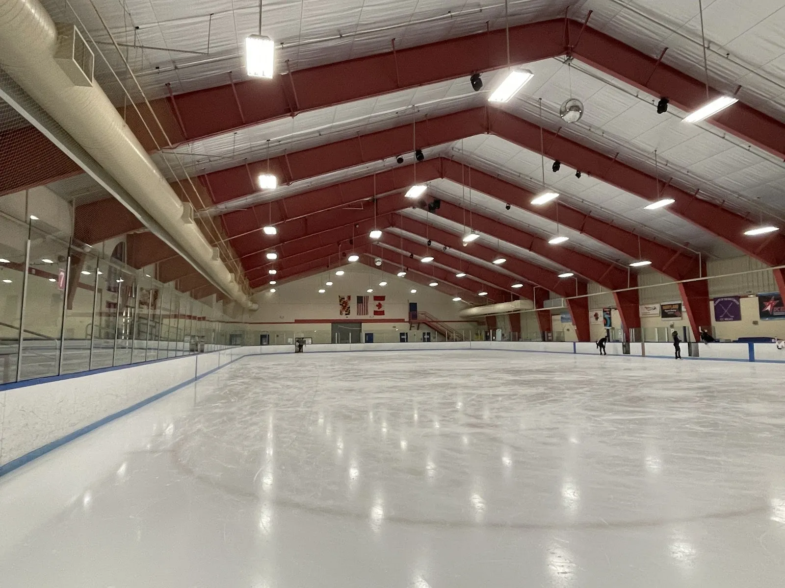 La pista vacía bajo las armaduras rojas de acero del techo de la arena, con vista a lo largo del hielo. — Wheaton Ice Arena
